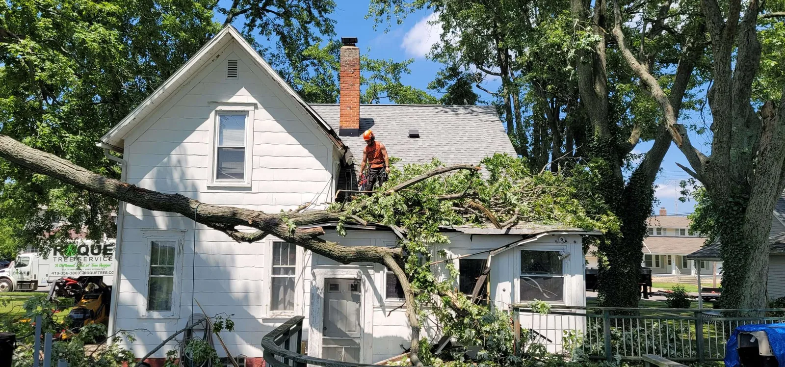 Broken tree limbs beside a house
